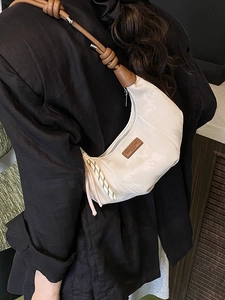 Minimalist white crescent dumpling bag with brown leather shoulder strap shown on model