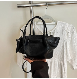 Detailed view of black pebbled leather bucket bag with a silver heart-shaped pendant
