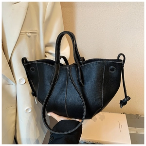 Detail of black pebbled leather tote bag with white contrast stitching and tie detail