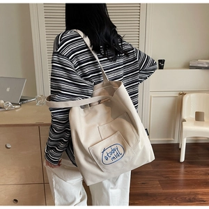 Close-up of minimalist off-white canvas tote bag featuring blue #today mood embroidery