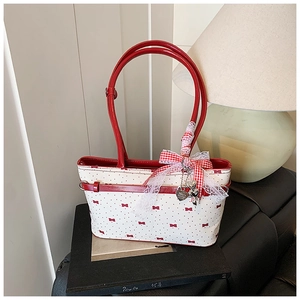 Dettaglio borsa in tela bianca con motivo a fiocco rosso, pizzo e pendente a cuore