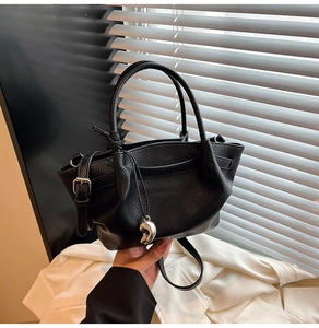 Close-up of black pebble leather texture and silver pod pendant on a bucket bag