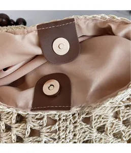 Detail of woven straw tote bag featuring magnetic snap closure and smooth brown lining