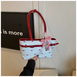 Dettaglio del manico in pelle rossa e charm a fiocco su borsa a spalla blu a pois