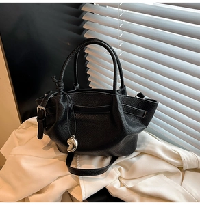 Detail of black lychee grain leather bucket bag with silver metal pendant and strap
