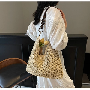 Detail of woven straw tote bag featuring decorative brown wooden beads and intricate crochet