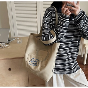 Detail view of a beige canvas tote bag with today midi text pocket in a daily setting