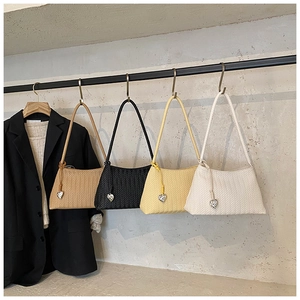 Detail of hand-woven shoulder bags in four colors with silver heart-shaped metal charms