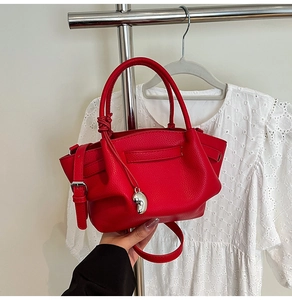 Macro shot of red leather bucket bag with silver heart charm and adjustable strap
