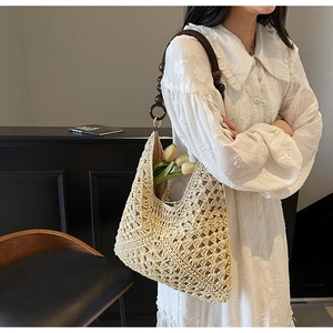 Detail of beige woven straw tote bag with beaded handle and floral lining for beach