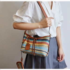 Detail of colorful striped woven crossbody bag with brown leather trim and mini pouch
