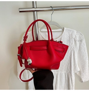 Close-up of red lychee pattern leather bucket bag with silver charm and detachable strap