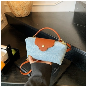 Detail of blue denim shoulder bag with silver studs and brown leather handle