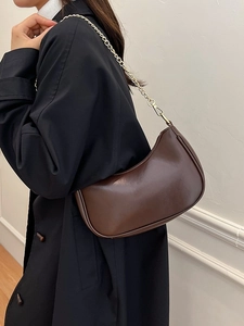 Minimalist coffee brown crescent shoulder bag with golden chain on black coat