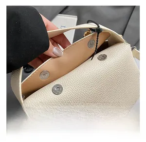 Detail of white litchi leather bag showing four magnetic buckles and metal hardware