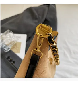 Gros plan du fermoir en métal doré et chaîne sur un sac à bandoulière en daim kaki