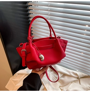 Close-up of red lychee pattern leather bucket bag with silver hardware and pendant