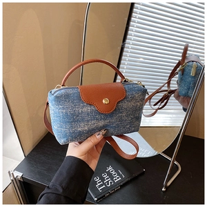 Detail of blue denim and brown leather contrast handbag with gold metal buckle