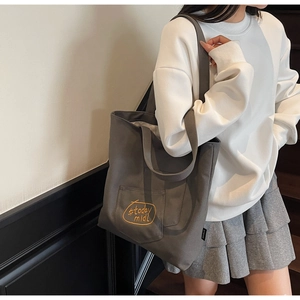 Detail of dark gray canvas tote bag featuring embroidered yellow circle and text logo