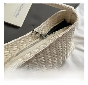 Detailed close-up of a silver metal zipper on a beige woven bucket bag with lining