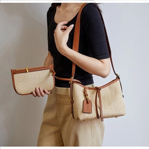 Close-up of straw shoulder bag and clutch set with brown leather trim and golden hardware