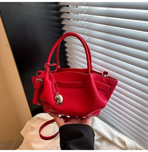 Detailed macro view of red lychee grain leather bucket bag with silver heart pendant