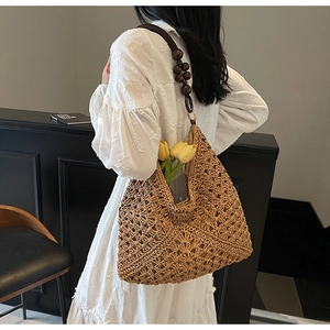 Detail of bohemian straw tote bag with intricate hollow crochet and wooden bead strap