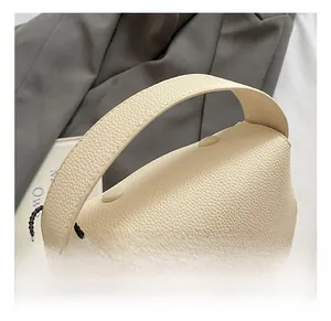 Detail of cream white litchi grain leather handbag with wide strap and gold chain detail