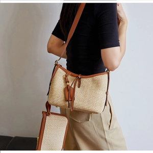 Close-up of woven straw shoulder bag with brown leather trim and matching pouch detail