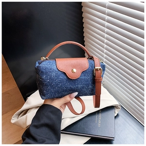 Detail of blue denim crossbody bag with white polka dots and brown leather flap