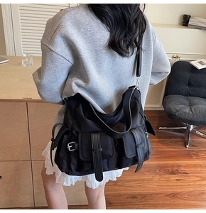 Detail of a large black nylon tote bag with utility pockets and premium adjustable buckles