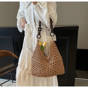 Detail of woven straw tote bag with brown wooden bead handles and white lace dress