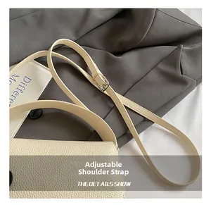 Detail of adjustable strap with silver buckle on cream lychee grain leather handbag