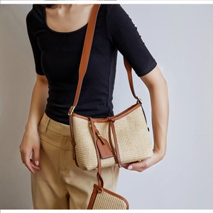 Detail of straw woven shoulder bag with brown leather trim and mini hanging pouch
