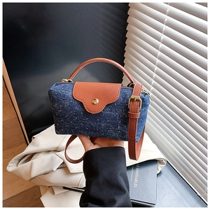 Detail of blue denim and brown leather mini crossbody bag with golden metal hardware