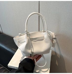 Detailed view of white pebble leather bucket bag with silver heart pendant and strap