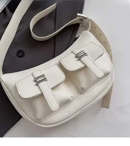 Detail of white leather shoulder bag with two utility pockets and silver metal buckles