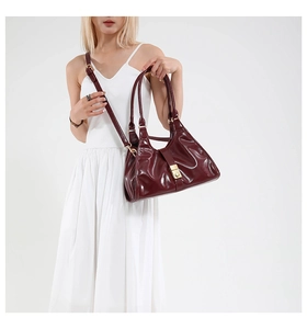 Détail du sac sous l'aisselle bordeaux brillant avec boucle en métal et forme en croissant