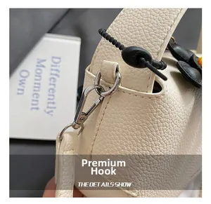 Close-up of premium metal lobster clasp and litchi grain leather strap on a white bag