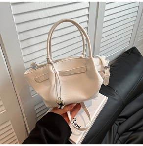 Close-up of white lychee pattern leather bucket bag with unique folded design and strap