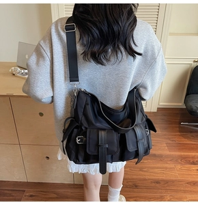 Detailed view of black nylon tote bag with functional pockets and adjustable wide strap