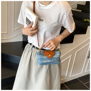 Close-up of mini denim crossbody bag with brown leather flap and golden snap button