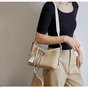 Detail of hand-woven straw shoulder bag with white leather trim and mini pouch attachment
