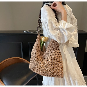 Detail of woven straw tote bag with retro wooden bead shoulder strap on a white dress
