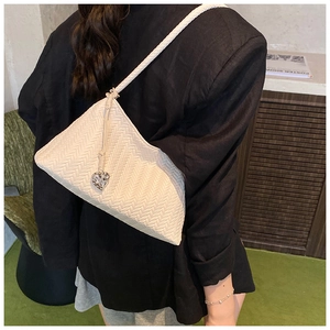 Detail of cream woven shoulder bag with silver heart charm and intricate V-stitch texture