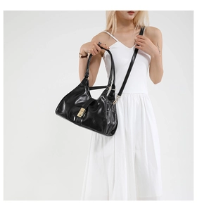 Détail d'un sac à bandoulière en cuir verni noir avec un fermoir carré doré brillant