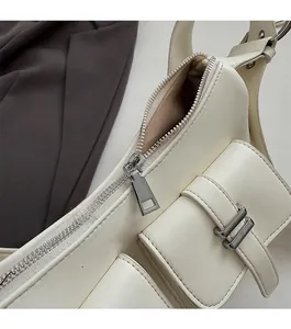Detail of cream leather shoulder bag showing smooth zipper and side pocket with buckle