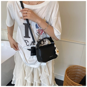 Chic black litchi pattern mini handbag styled with a daisy charm on a model