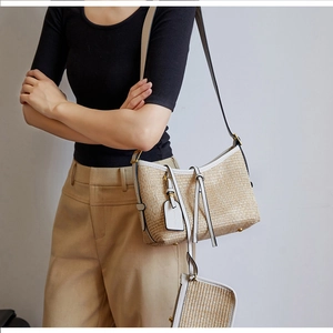 Detail of straw shoulder bag with cream leather trim and matching mini pouch on model