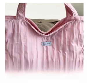 Dettaglio della borsa tote rosa a pieghe con trama verticale ed etichetta del brand